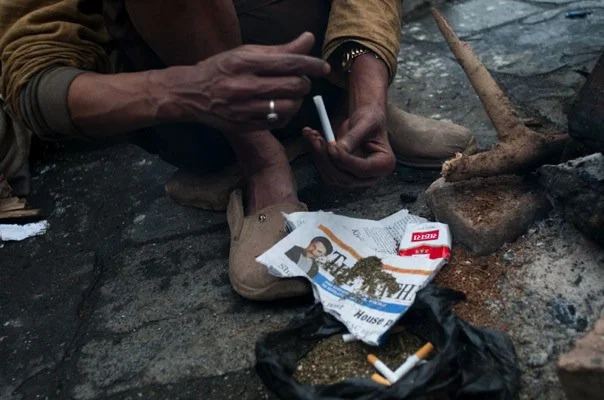 Throughout the day, they just go through it mechanically: Empty the cheap cigarette, mash it up with the weed, and pack it back in.