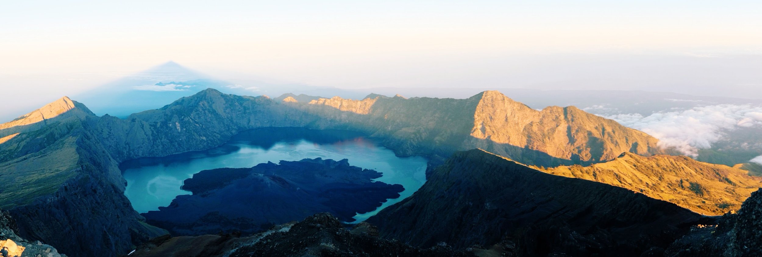 Sunrise from the summit of Mount Rinjani. The dark shadow of the peak extends far out into the ocean.