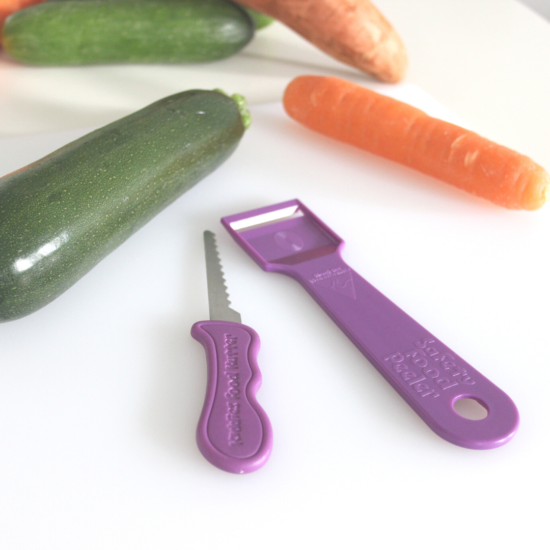 purple Kiddie's Food Kutter and Safety Food Peeler next to courgette and carrot