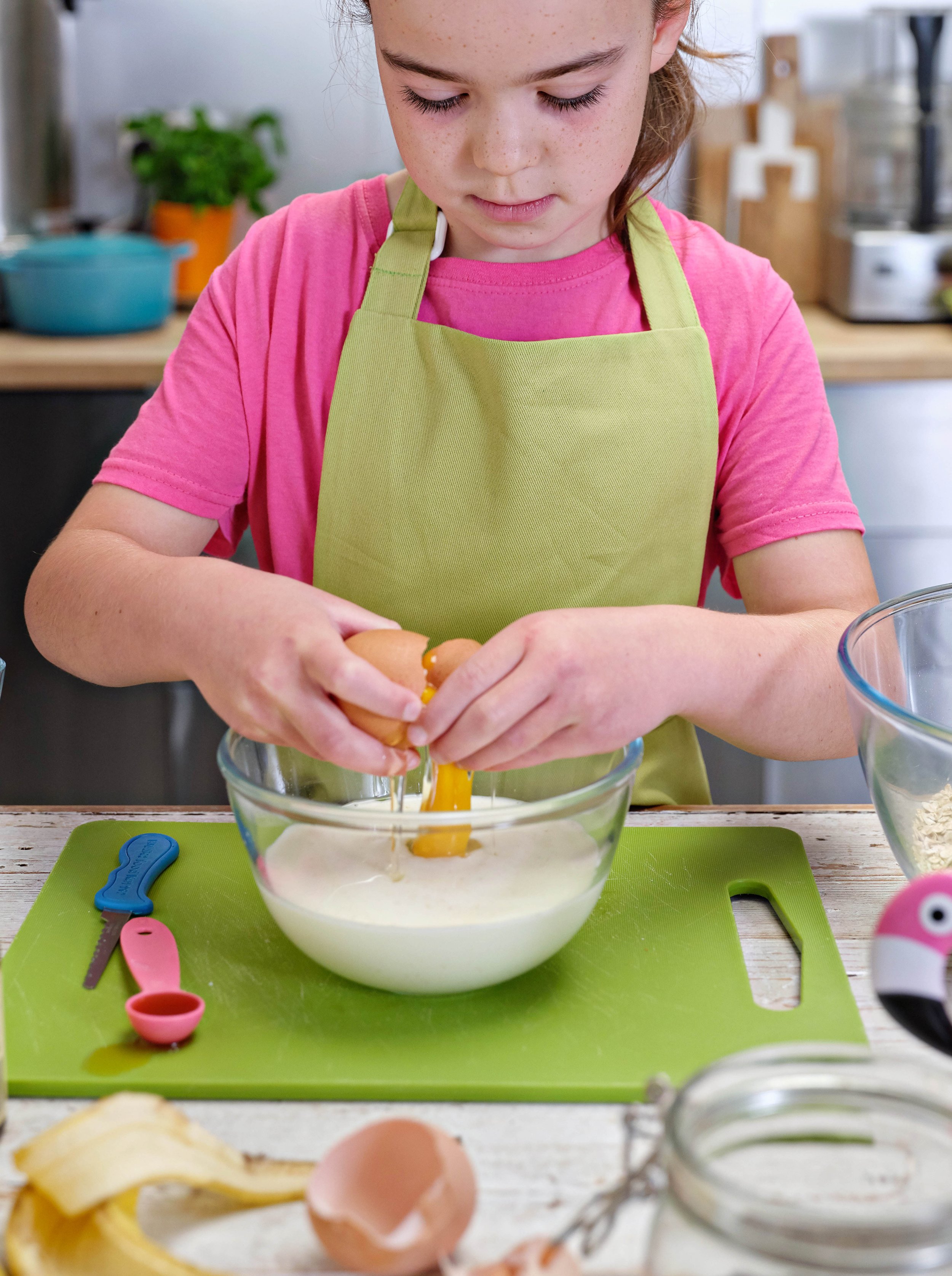 girl cracking egg with kiddie food kutter