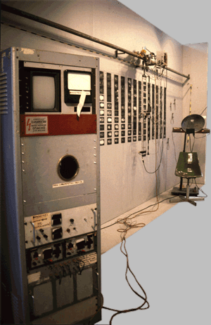 The entire Character Input reconstruction, displayed at ISEA '97. To the right is the subject scanning chair. Hanging from the track next to it is the X-Y visual input device, which first scans the subject and then moves over the visual database, finding correlations in facial structure between the subject and the faces in the database. When it find a strong area of correlation, it then refers to the character attribute data, stored in the research station, at the extreme left. Finally, predicted personality traits of the subject are displayed on the small round cathode tube of the research station.