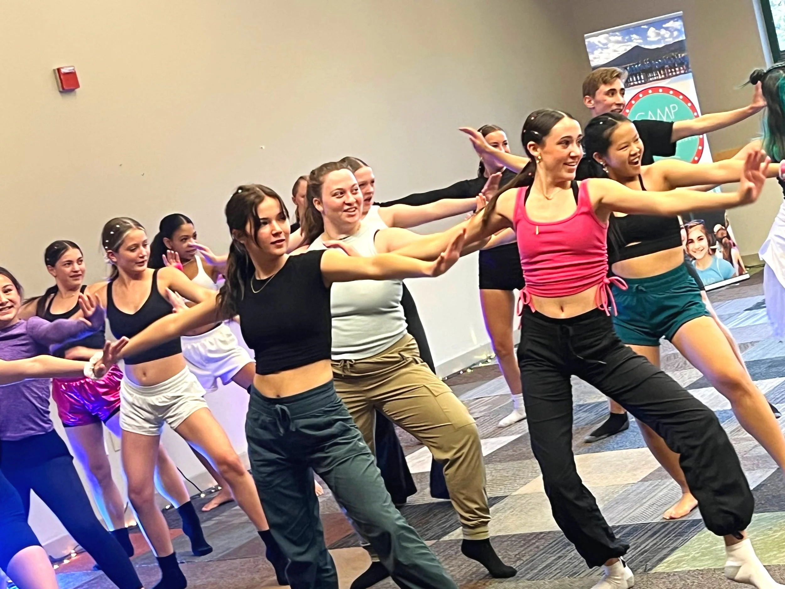 A diverse group of summer dance campers in a dance pose while partaking in a dance workshop