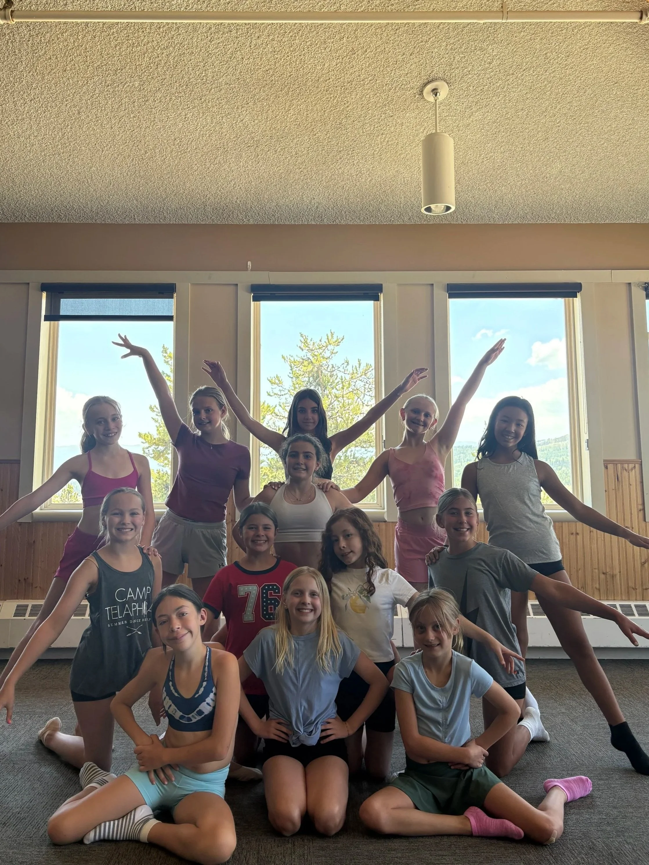 A diverse group of summer dance campers in a dance pose while partaking in a dance workshop