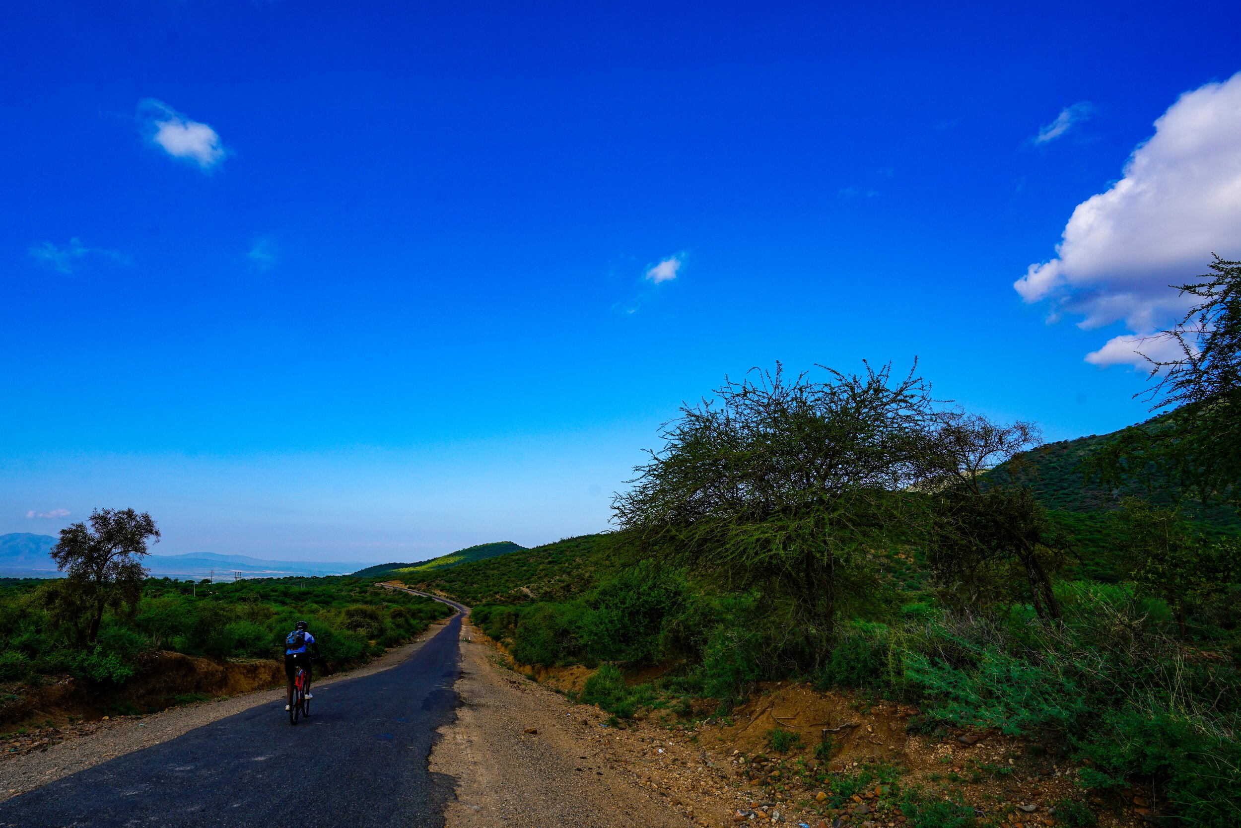  Official Day 1: 82.79 KM. 1626m of elevation loss. 357m of elevation gain.  2805 Calories.   This is a long luxurious descent. We start at dawn and the ridge of the western edge of the Rift Valley casts a deep dark shadow over the road as we wind do