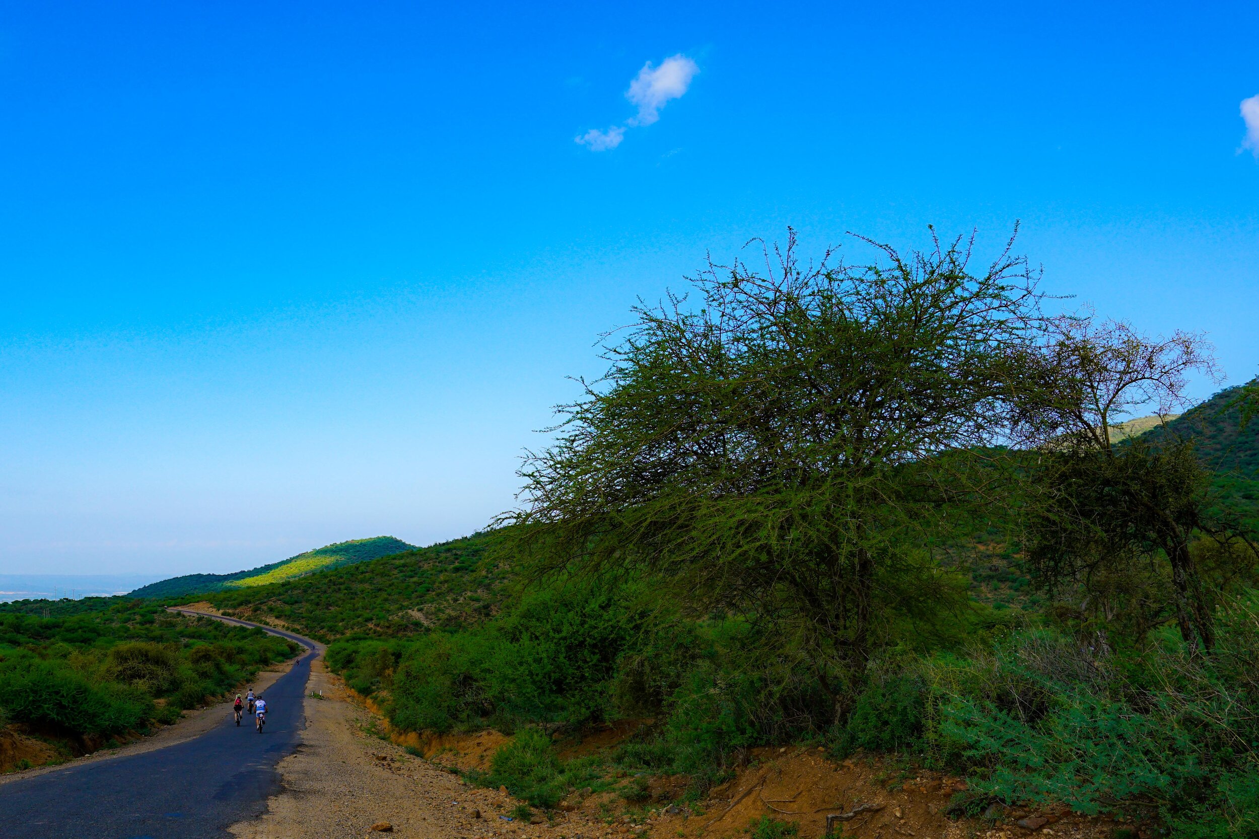  Three things about cycling in Africa.   1.  Big wide skies.  2.  Lush verdant greens.  3.  Long winding roads.   and 4… as always… the people we cycle with.    Here goes my ‘bestie’, my ‘aunty’ Shelley.  And John, the man whose perseverance encourag
