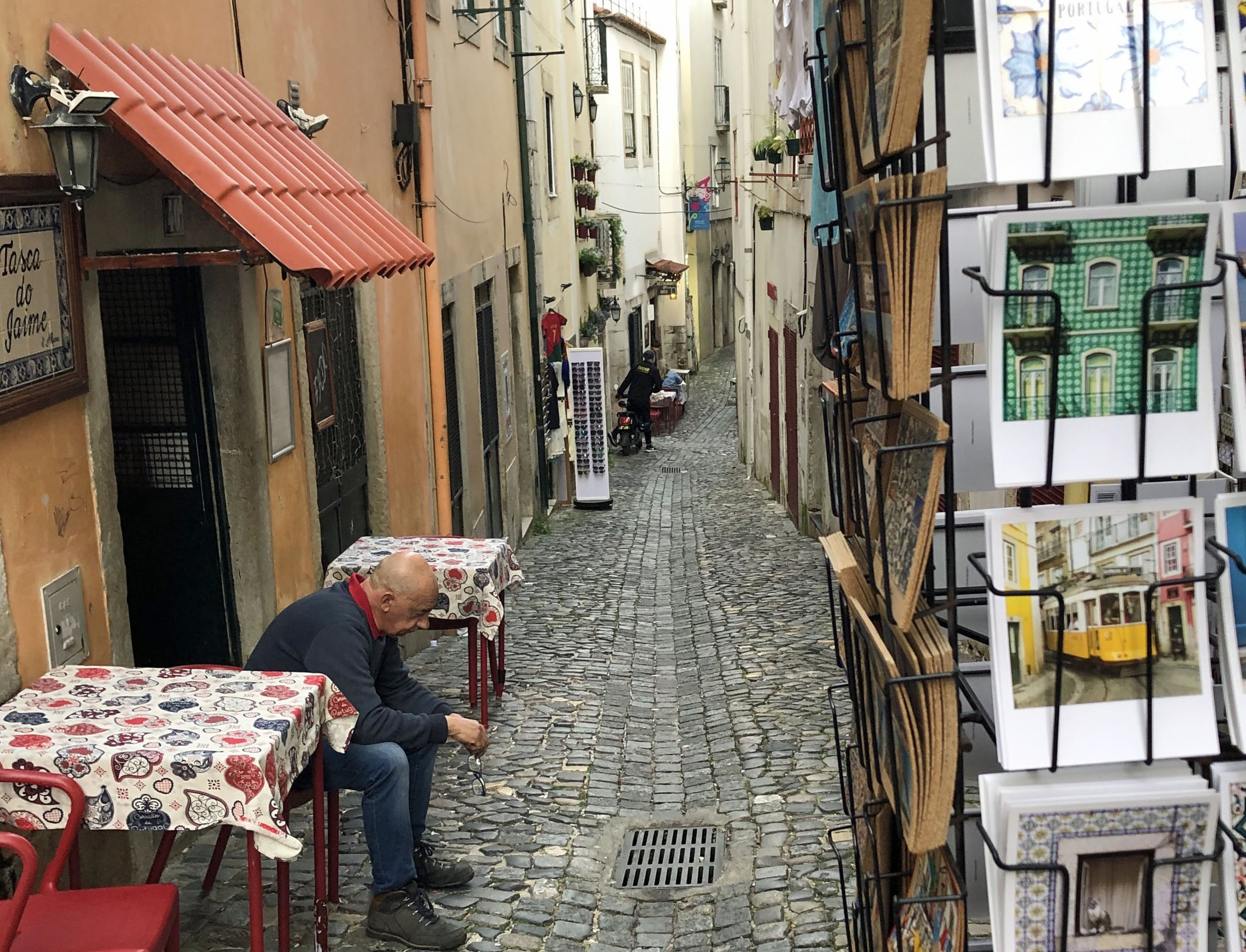 Man sits at outdoor table at Tasca do Jaime, a small Alfama restaurant offering intimate performances of fado, traditional Portuguese music heard in Lisbon and Coimbra.