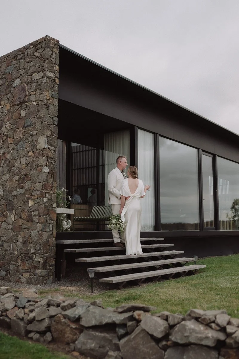 bride and groom standing on the steps of Seastone in Swansea Tasmania