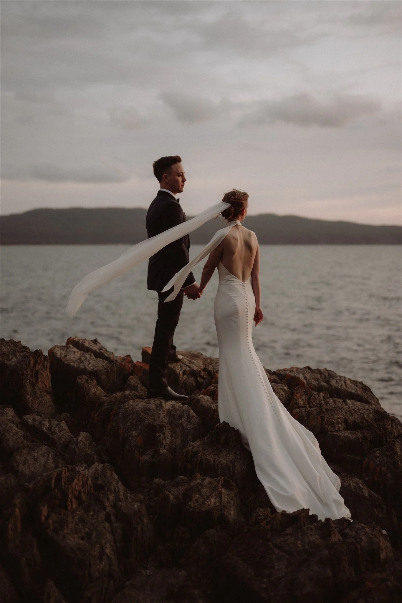 bride and groom standing on a cliff in tasmania