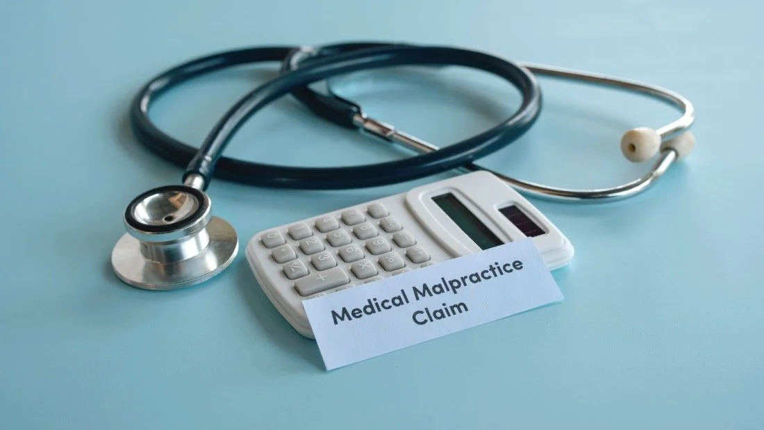Stethoscope and white calculator with medical malpractice claim text