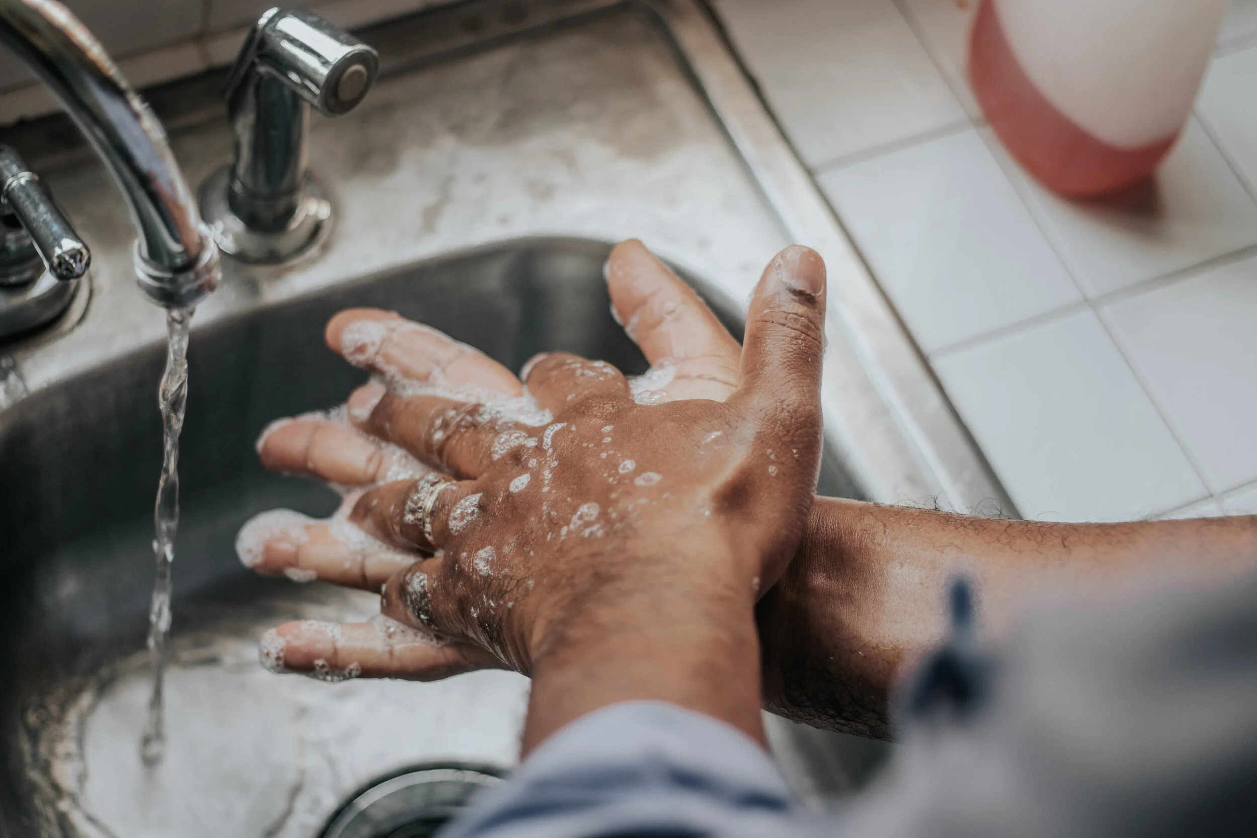 Staying informed as we all stay home Close up of a pair of hands beneath a sink, washing. This image is used to show that sanitary practices are necessary to stop the spread of COIVD 19