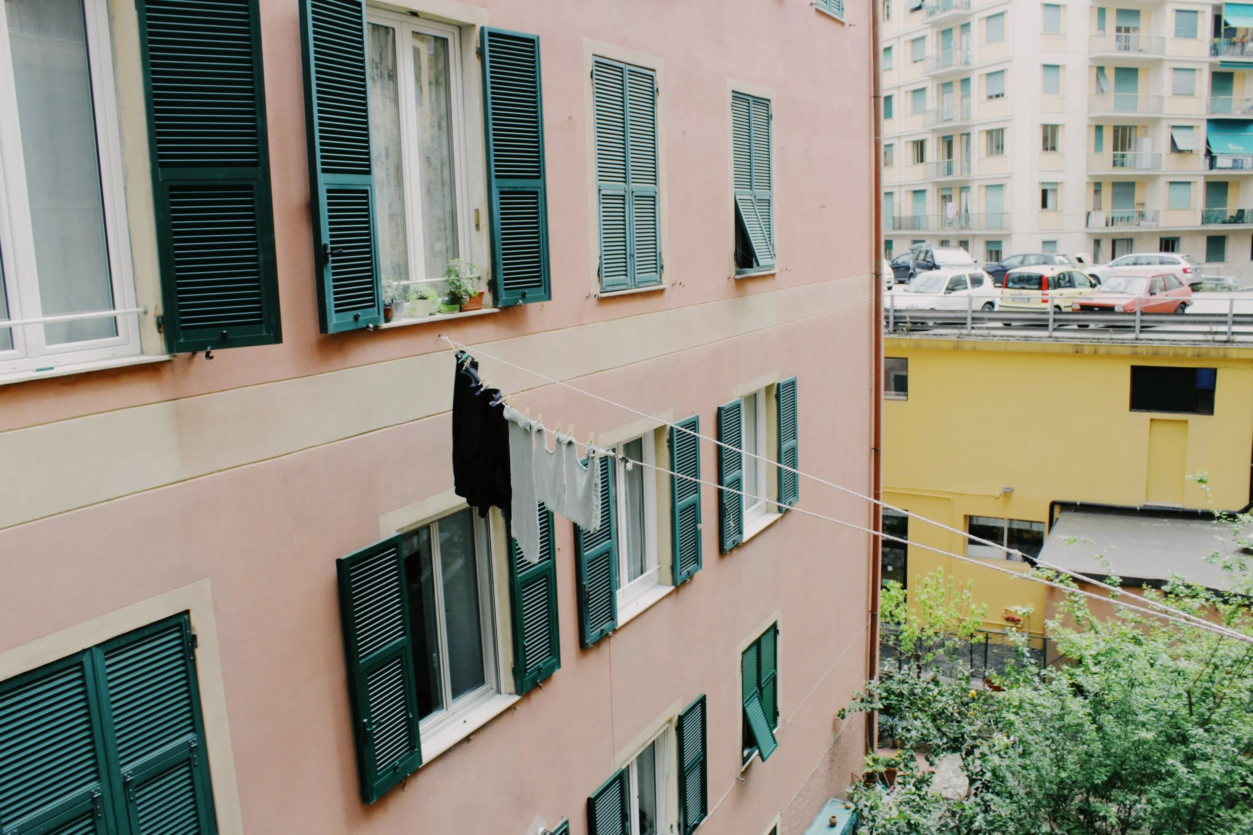 Image Description: An exterior shot of a pink building with laundry hanging out across a courtyard and airdrying