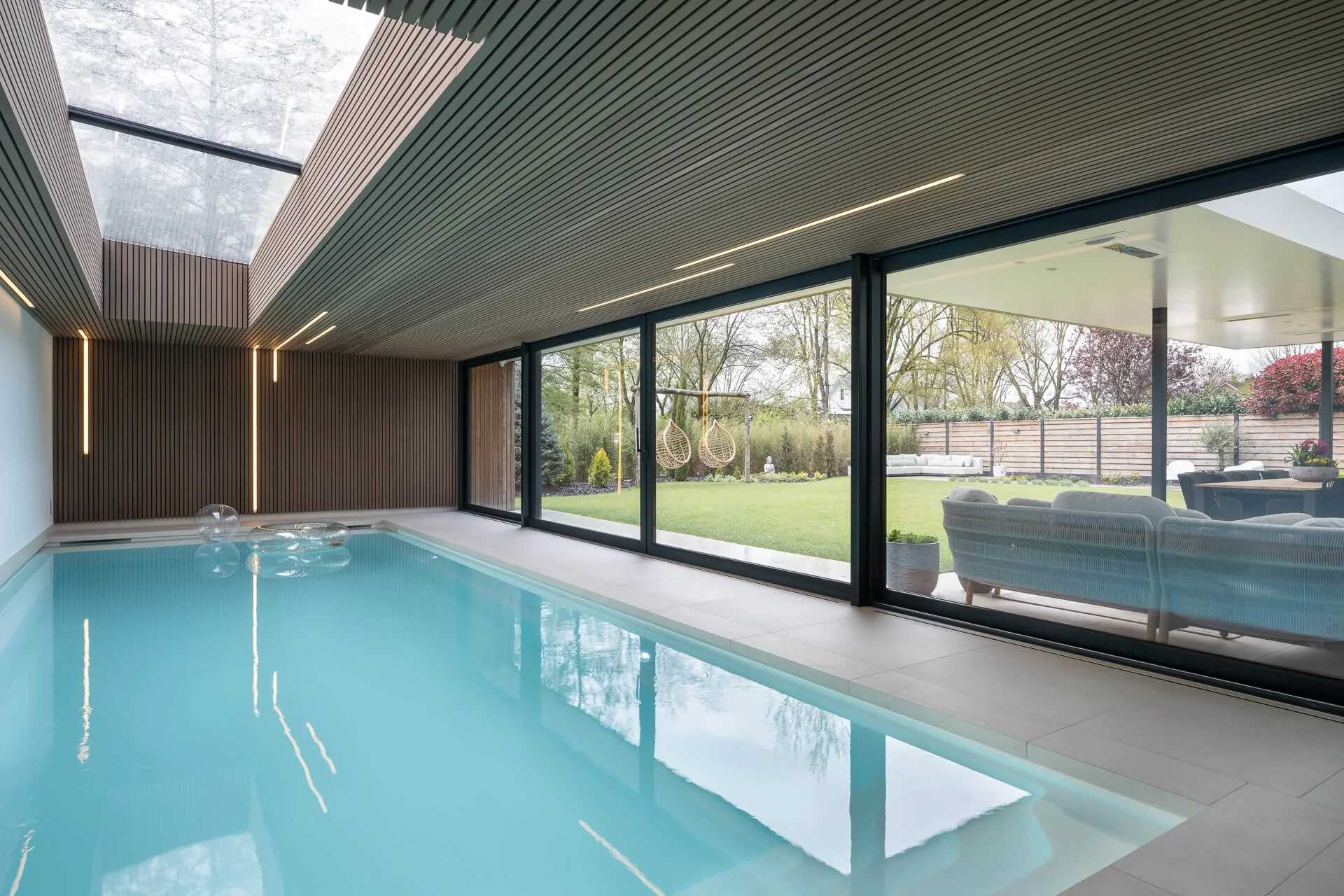 overdekt_zwembad_aanbouw_houten_plafond_lichtstraat_designverlichting_tuin_grote_schuifpui.jpg