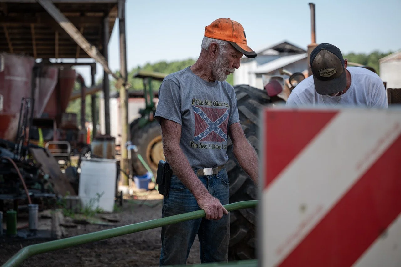 Kenney Barnard and one of his employees fixing a tractor at his farm in Amelia Court House in August.