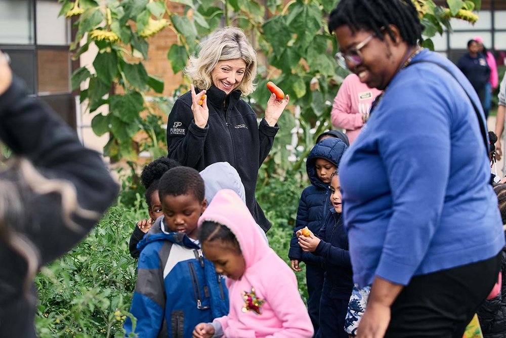 Erin Sherrow-Hayes from the Purdue Extension-Nutrition Education Program holds up fall tomatoes picked by the students as they eagerly search for more to harvest.