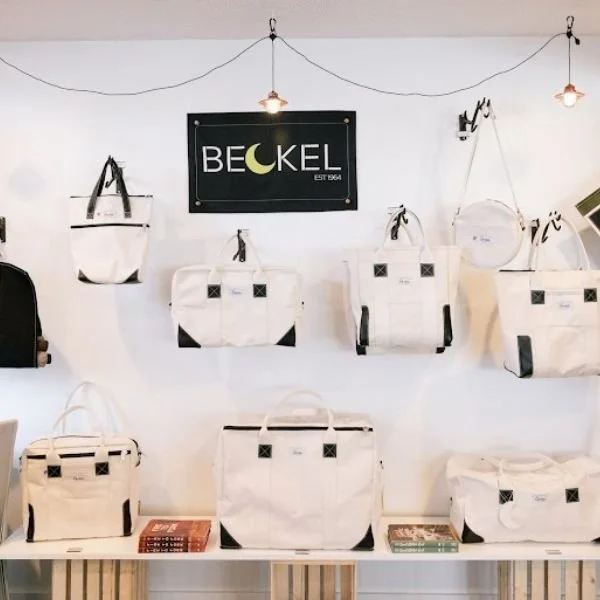 shop display of white canvas duffel bags and totes by Beckel