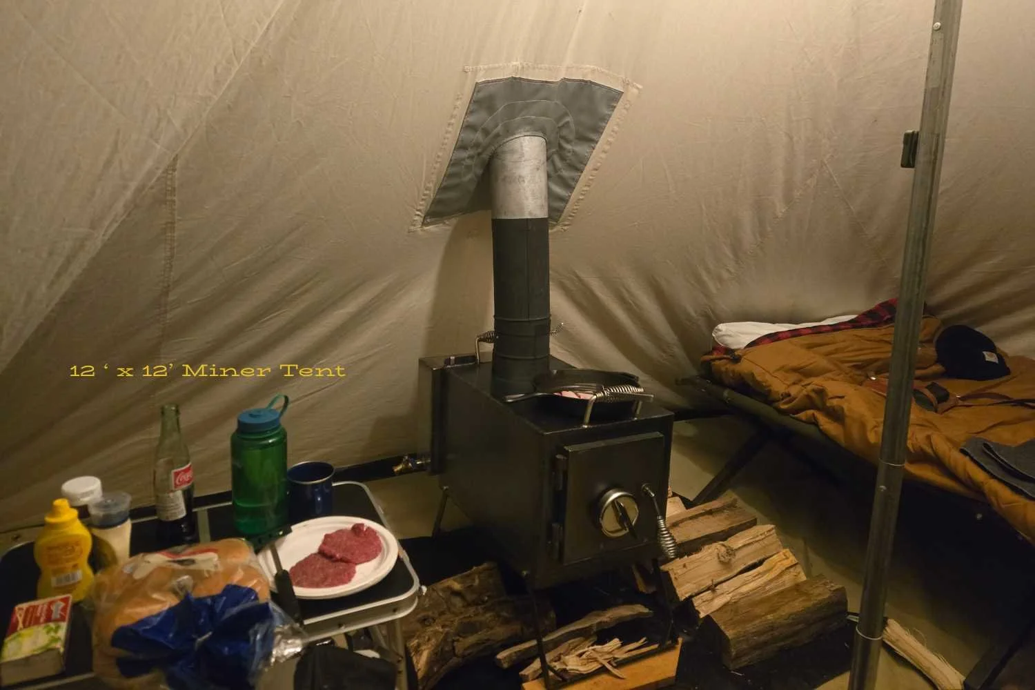 wood stove inside canvas tent with other camping gear