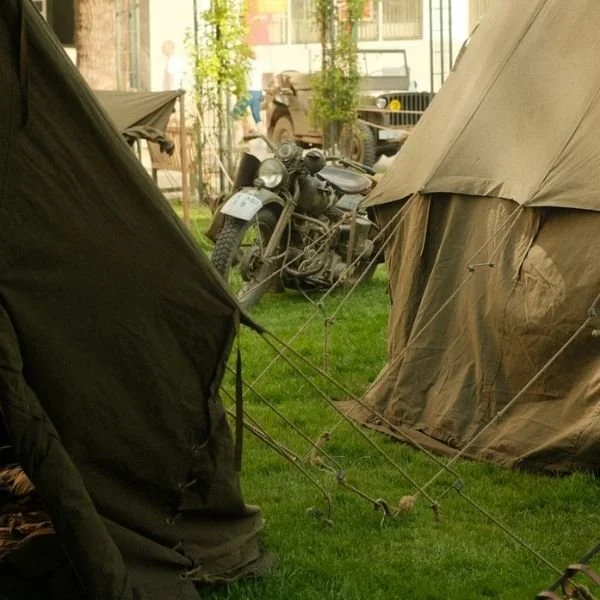 green canvas Sibley tents with motorcycle at World War reenactment