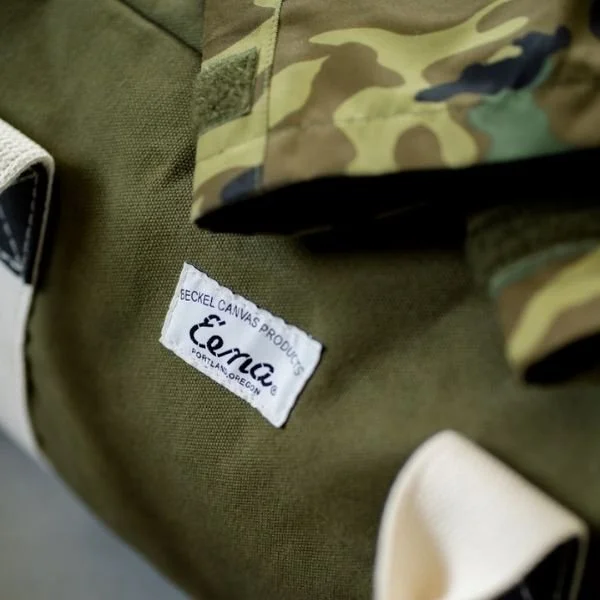 green canvas duffel bag with camouflage pattern coat sticking out