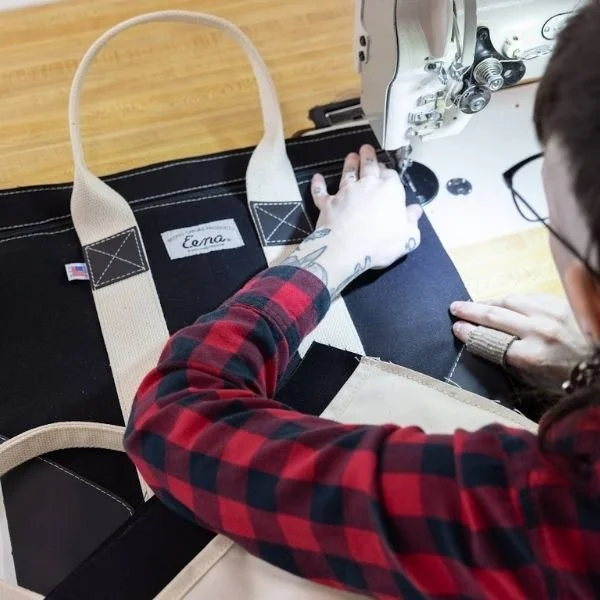 persson sewing double stitching onto black canvas tote bag