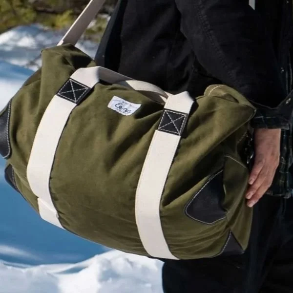 man carrying green canvas duffel bag by strap