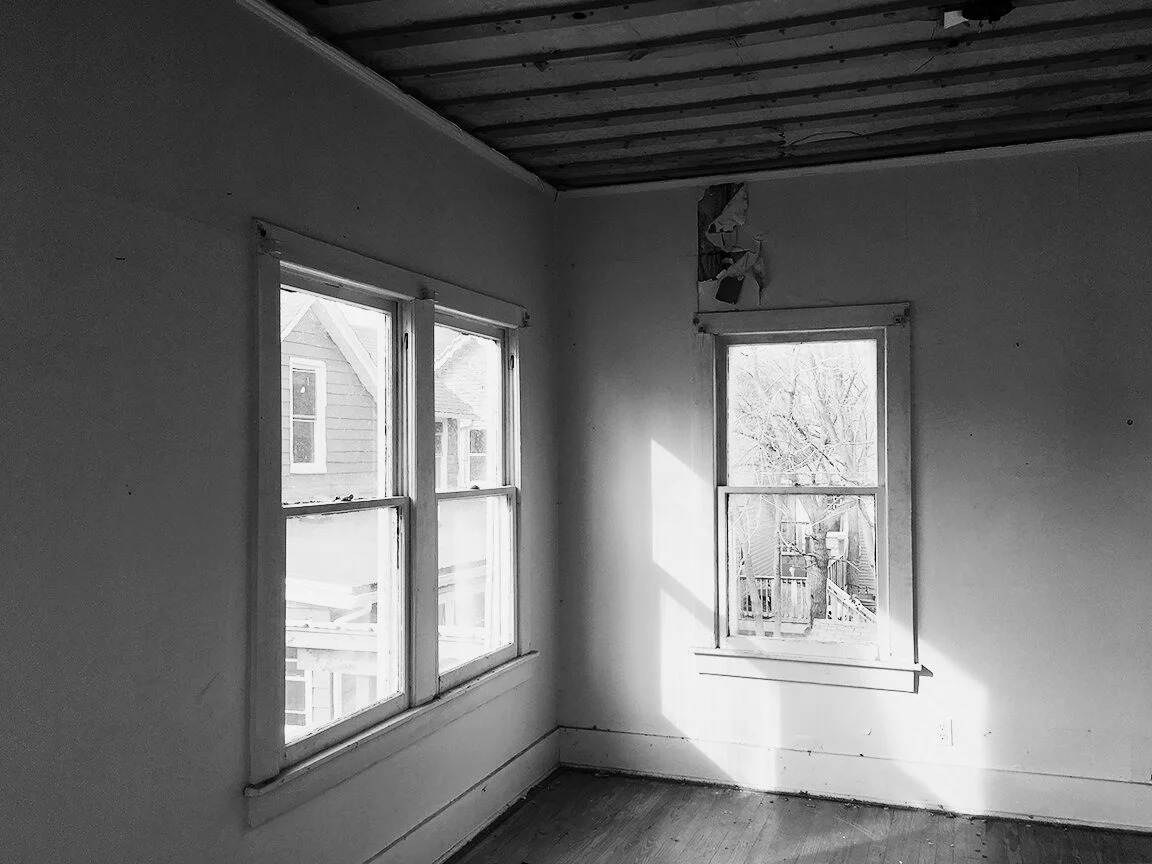 B&W picture of a remodel in progress showing old windows and battens on ceiling