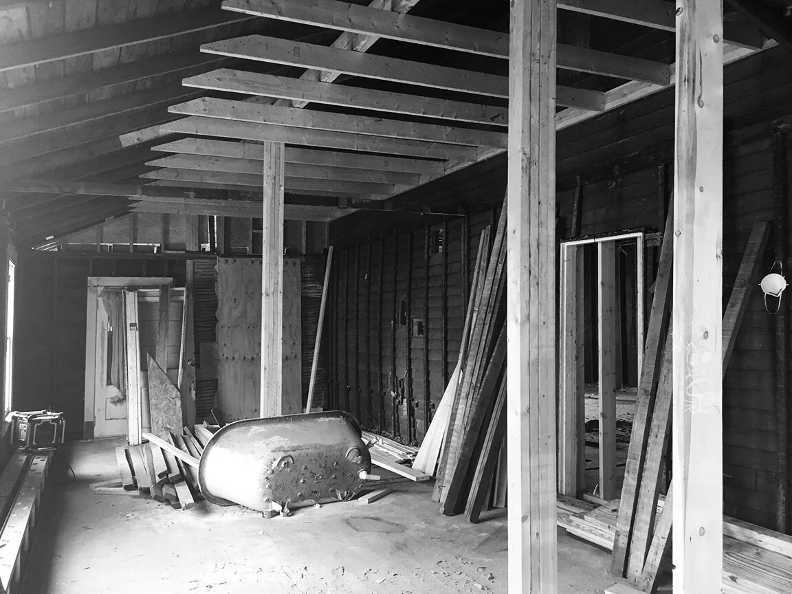 B&W picture of a home remodel in progress that shows exposed studs and collar ties on roof structure
