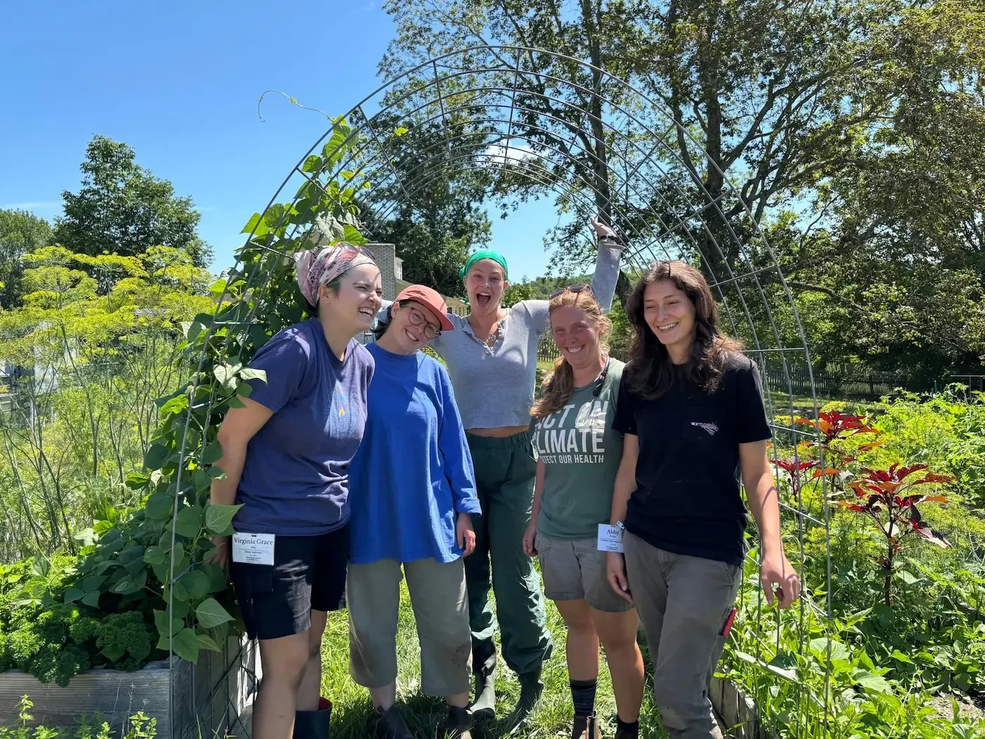 Farm apprentices and the farm manager smiling by a garden