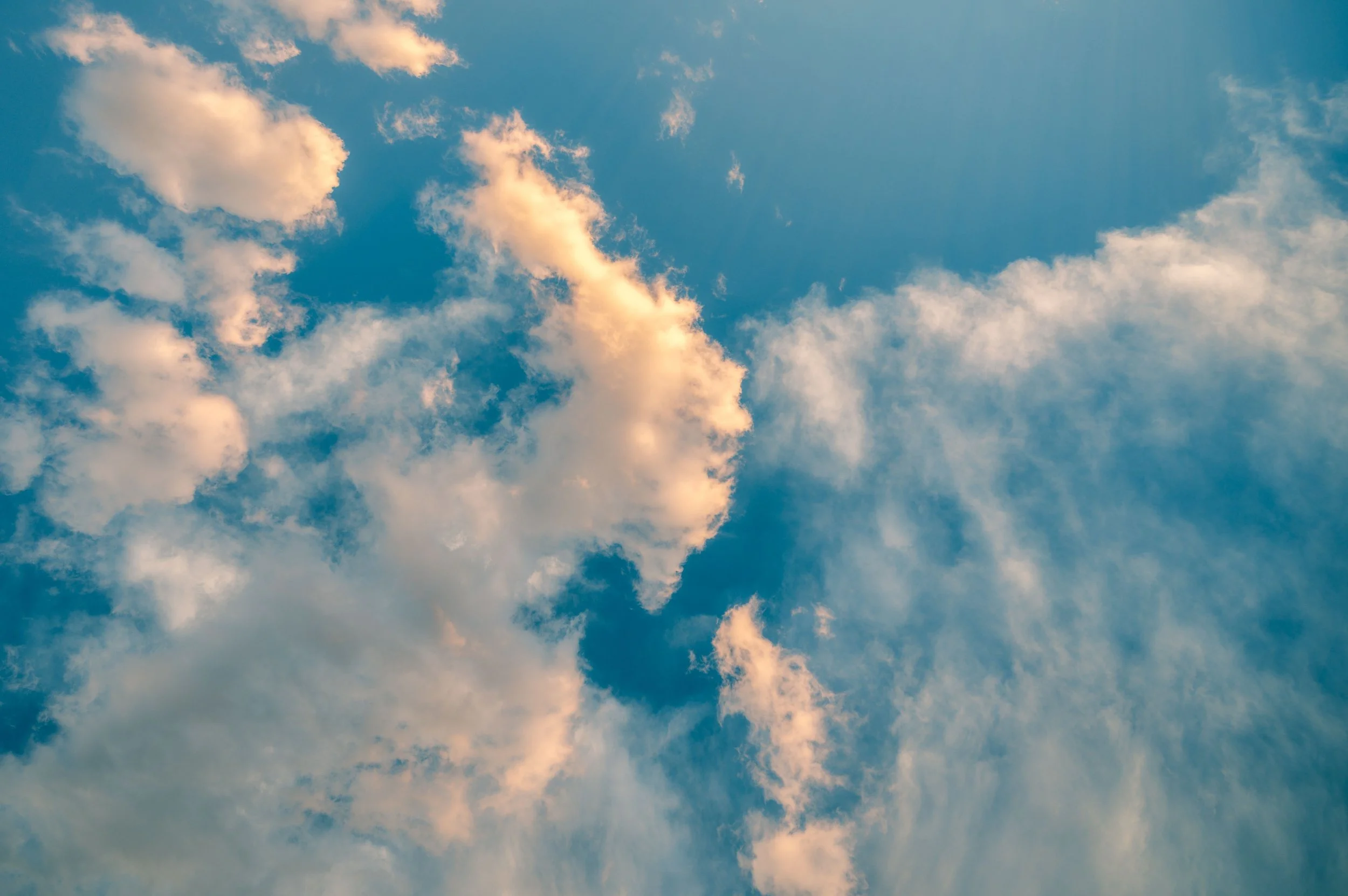 Blue sky with scattered white and light orange clouds.