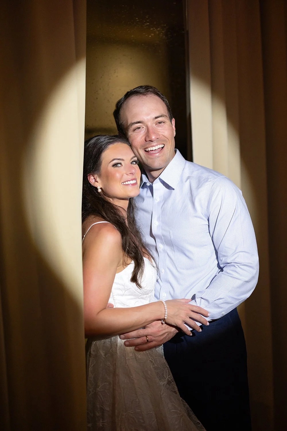 58 bride and groom smiling to the camera in a spotlight in the wedding reception party.jpg