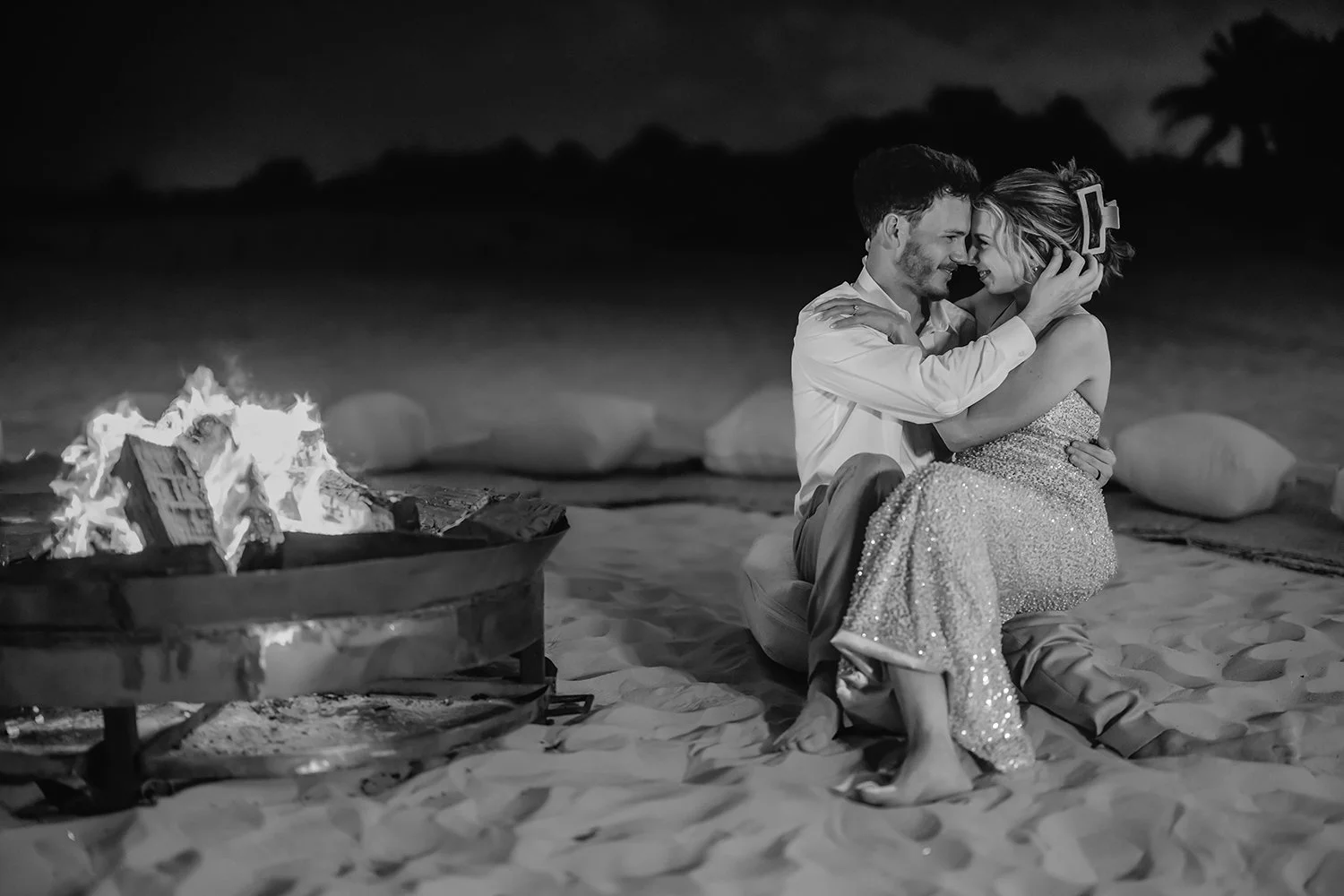 30 bride and groom cute face to face photo sitting near the bonfire at the beach at night.JPG