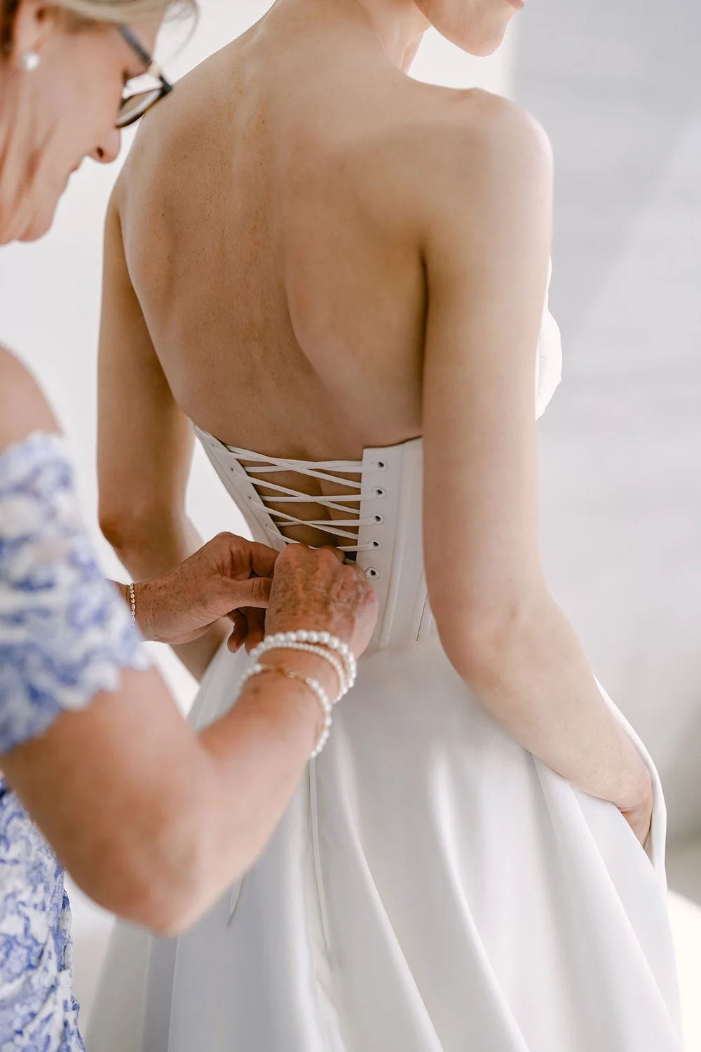 12.4 Mom of the bride helping bride getting ready for the wedding ceremony putting on her dress.JPG