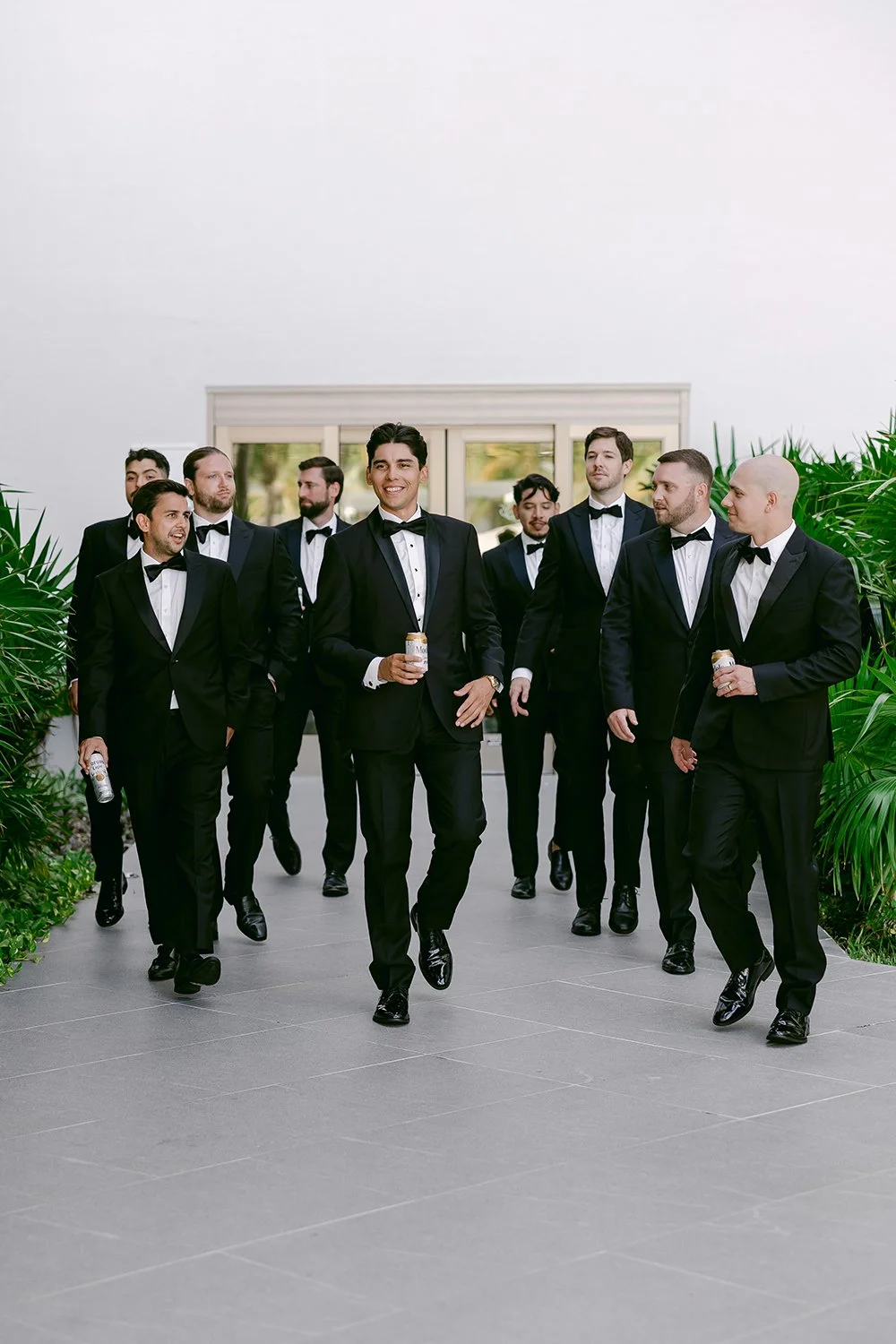 16 groom with groomsmen walking to the camera smiling wearing luxury tuxedos.JPG