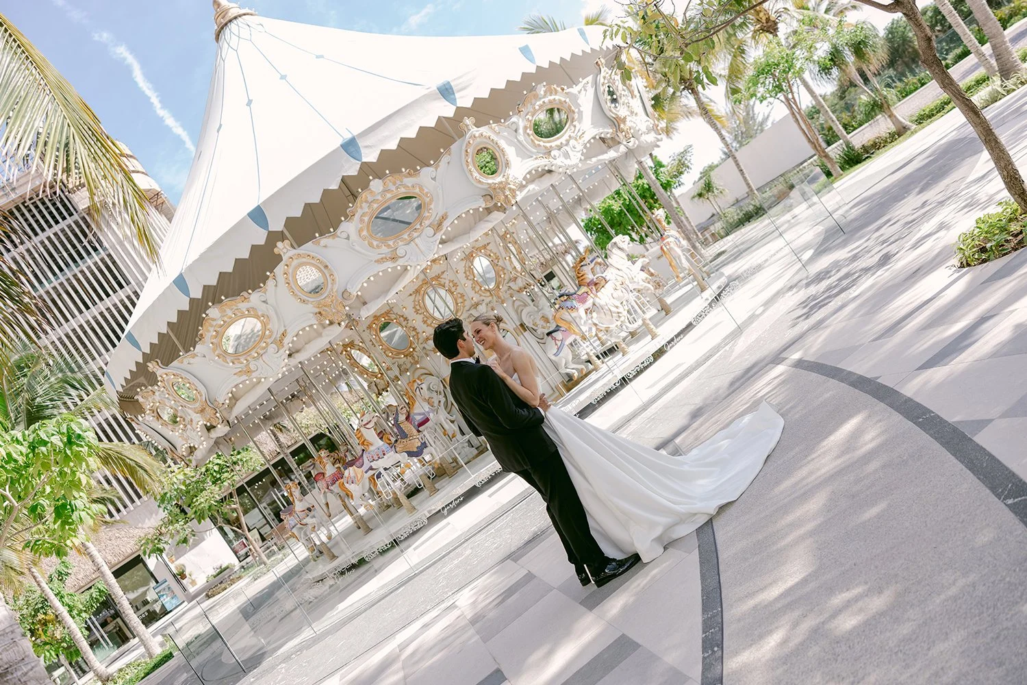 31 bride and groom looking at each other smiling in front of a carousel in garza blanca cancun.JPG