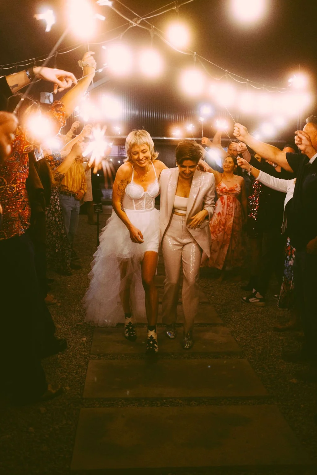 Two newlyweds celebrating beneath a sparkler exit with friends and family at an Austin wedding venue, capturing a joyful end-of-night wedding moment.