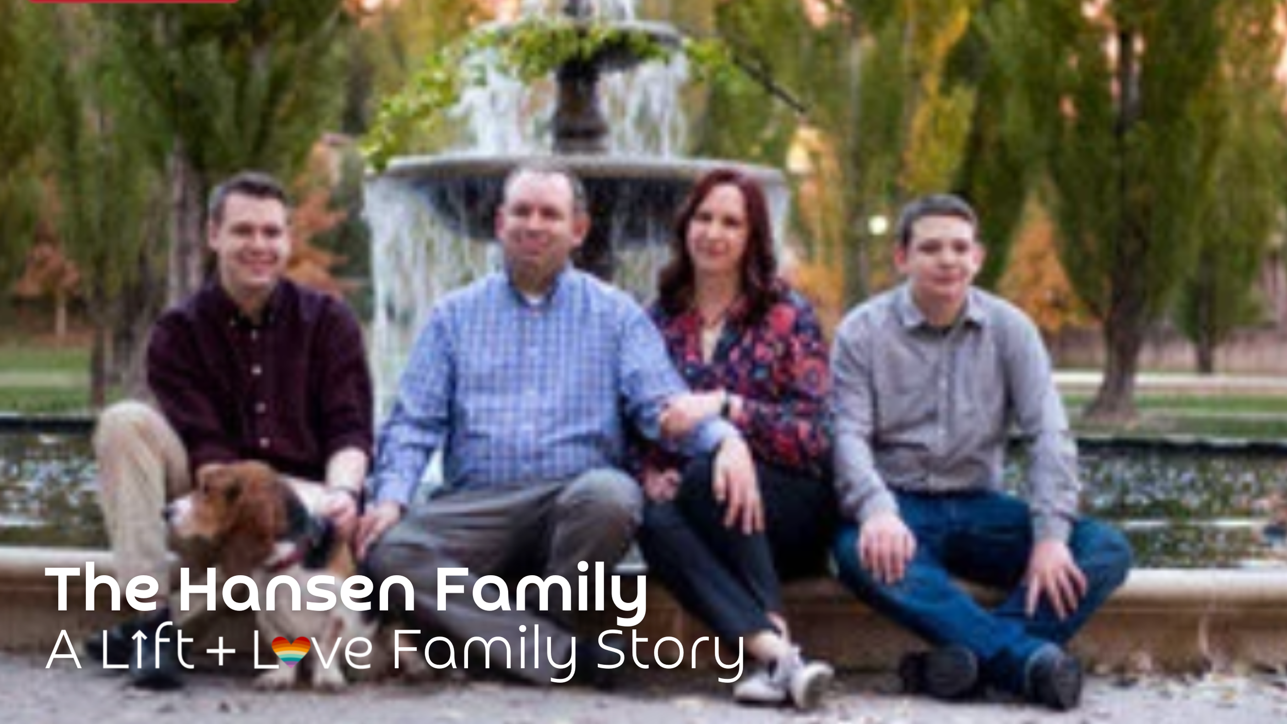 Family of five sitting on a fountain ledge in a park with trees and autumn foliage. The family includes two men, a woman, a boy, and a dog. The image contains the text 'The Hansen Family' and 'A Lift + Love Family Story' with a rainbow heart emoji.