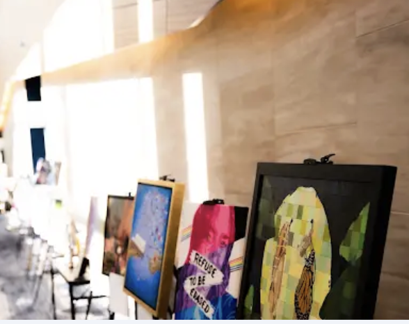 Art display with framed paintings or prints on a wall in a bright indoor space.