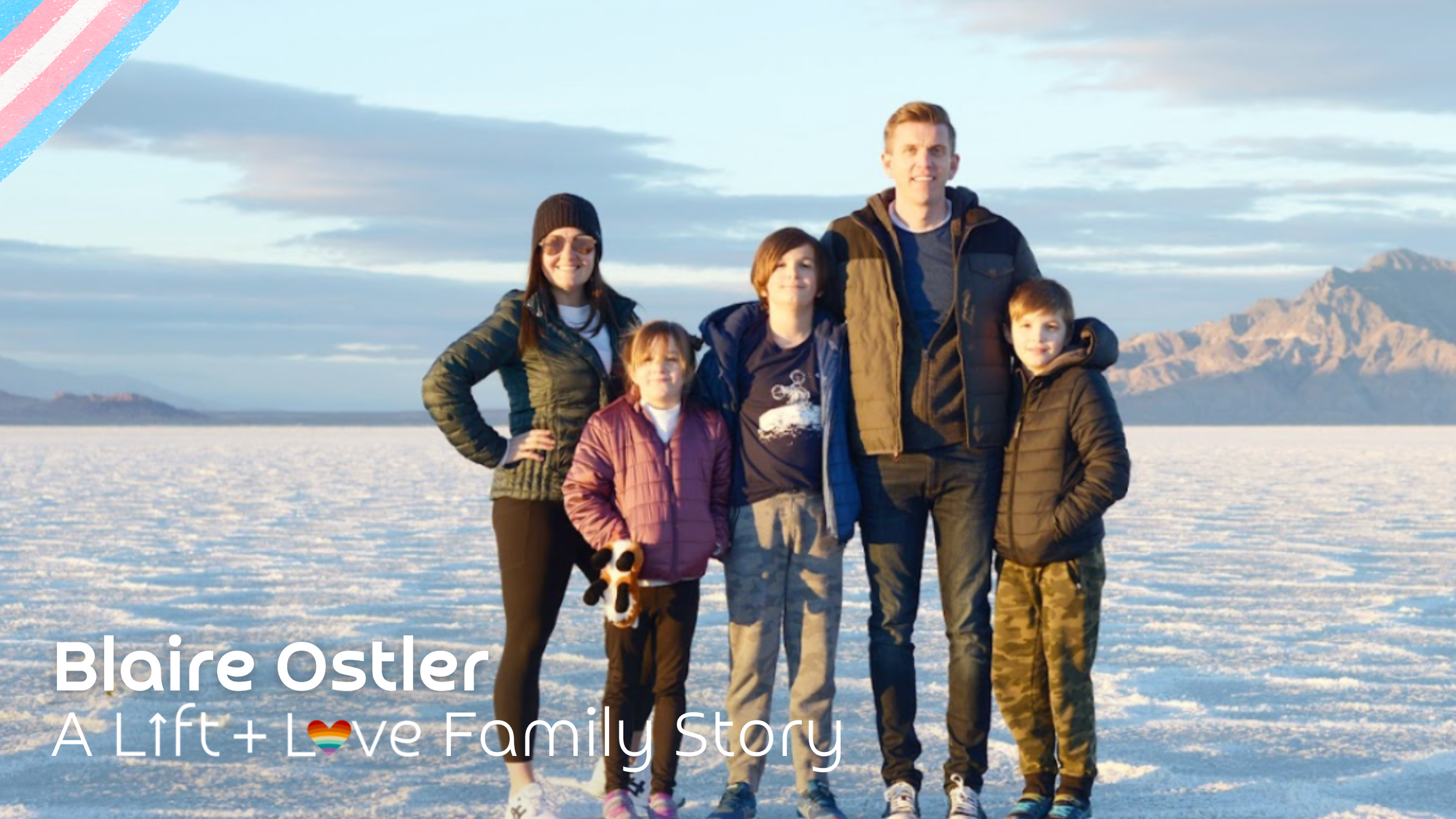 A family of six standing together outdoors in a snowy landscape with mountains in the background, smiling at the camera.