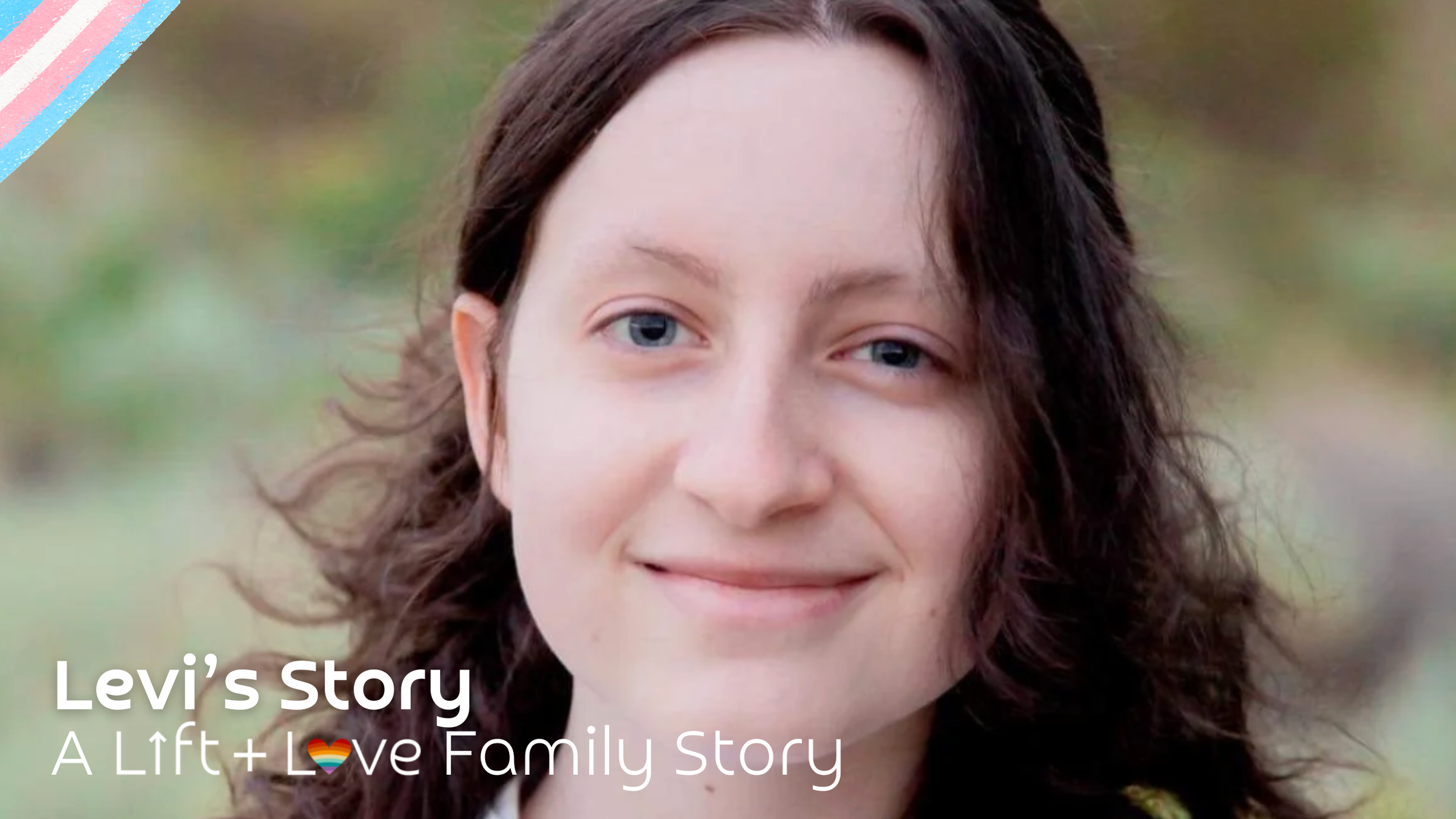 Close-up of a woman with long, wavy dark hair and blue eyes, smiling outdoors with blurred greenery in the background.