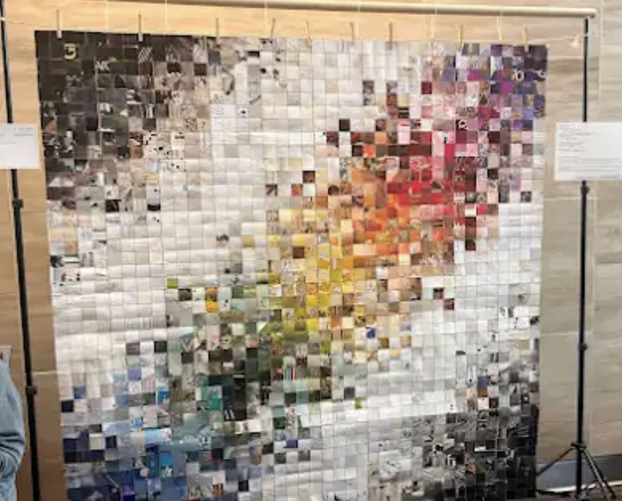 A mosaic art piece consisting of numerous small, square photos arranged to depict a person holding a pink flower, with some yellow and green elements at the bottom.