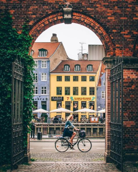 Eco Travel Guide to Copenhagen article. Image of girl on bike cycling through Nyhavn.jpg