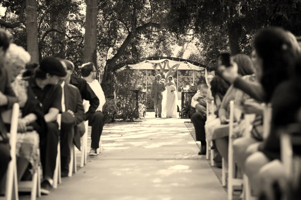 Father walks his daughter down the isle in beautiful outdoor garden ceremony