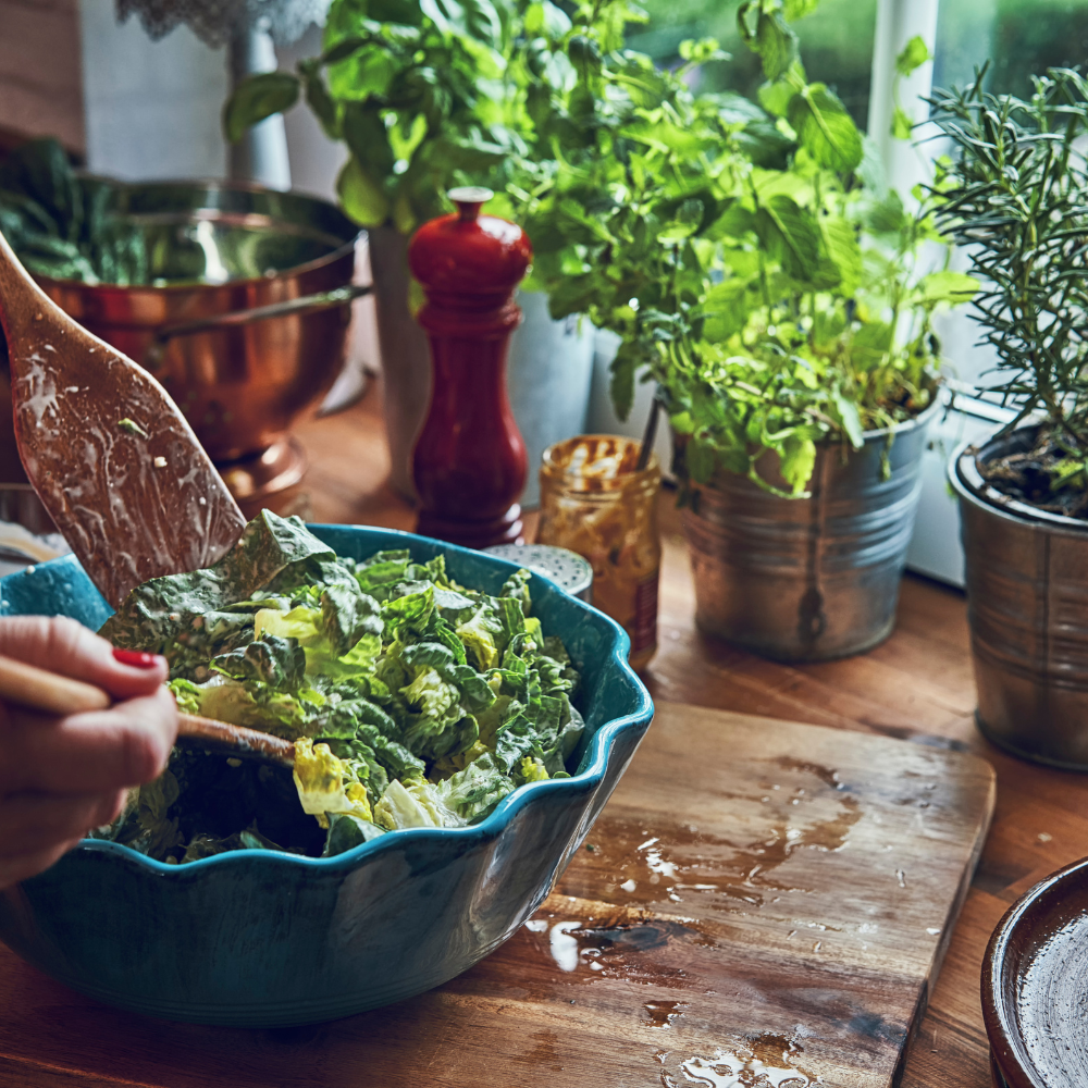 Tossing kale, romaine lettuce with homemade Caesar dressing