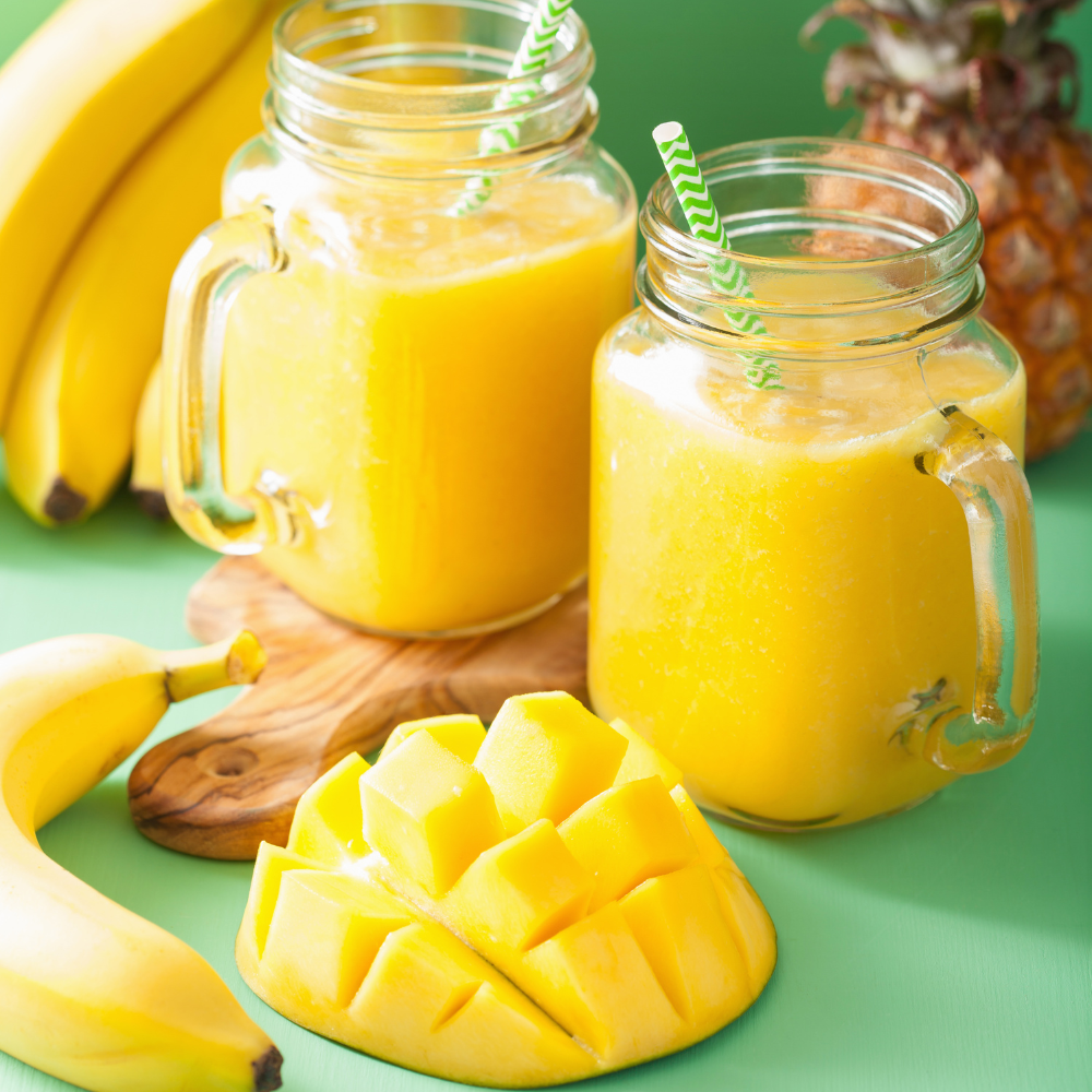 Creamy mango pineapple smoothie in a clear glass with a tropical garnish.