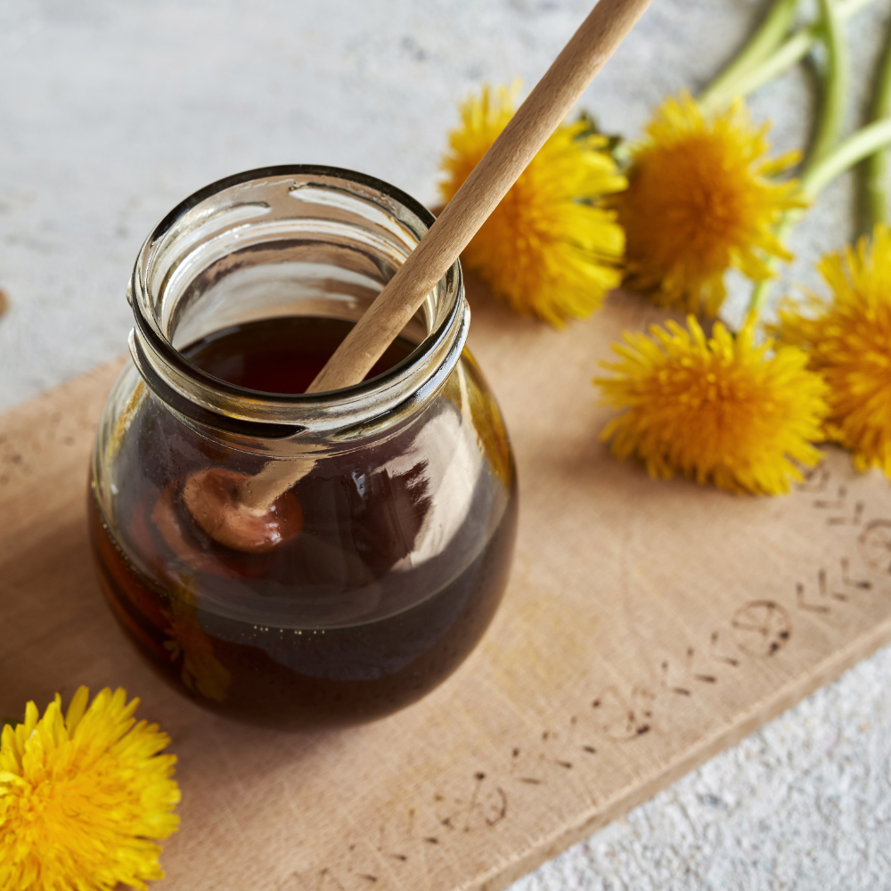 Raw honey in a glass jar with a spoon, used as a natural sweetener for dandelion tea