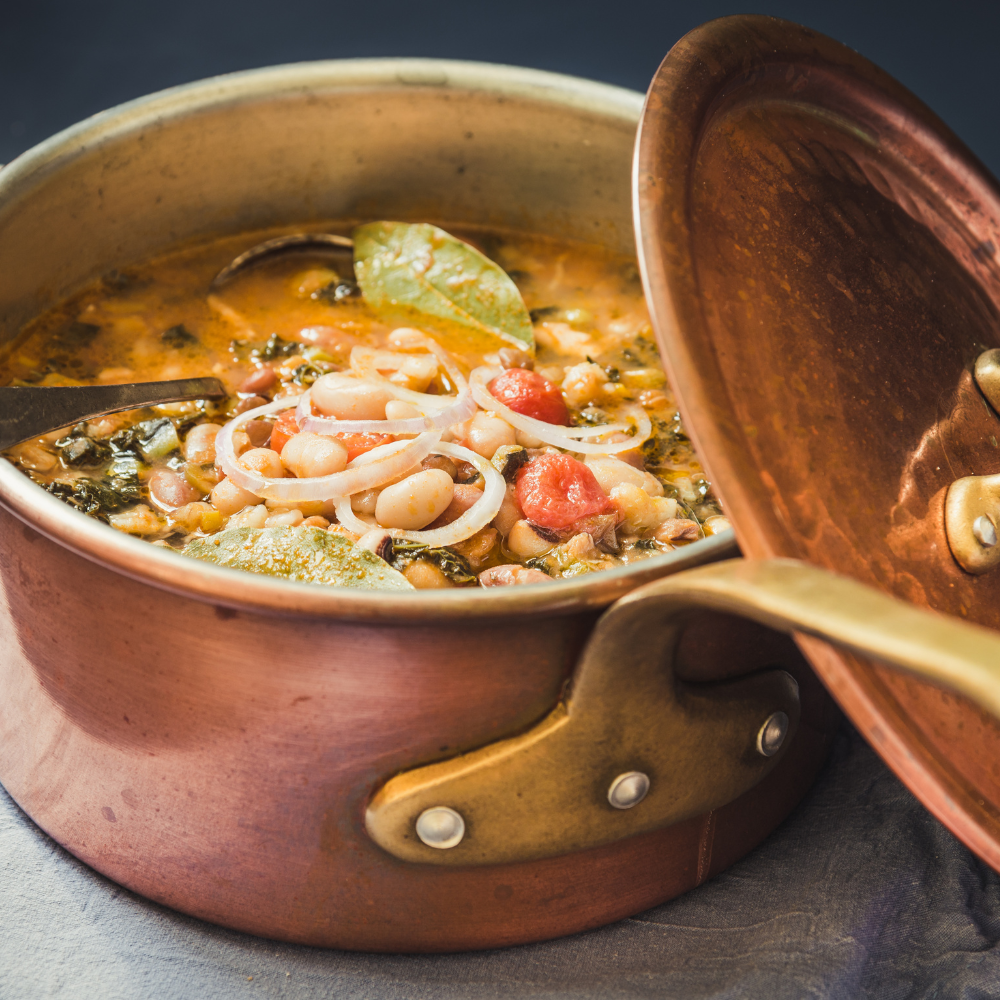 Ham and bean soup simmering in a pot with vegetables and smoked ham.
