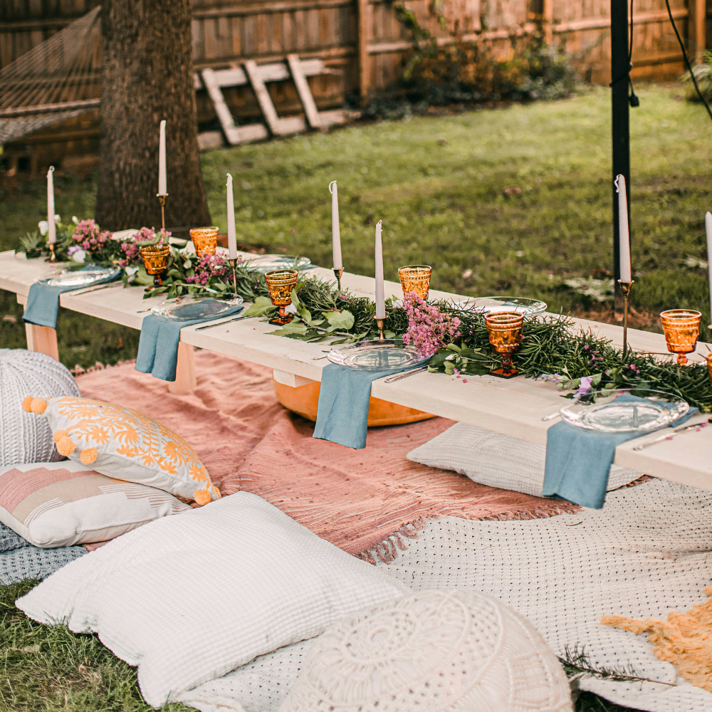 Botanical picnic garden party with blankets, wildflowers, and low table setup