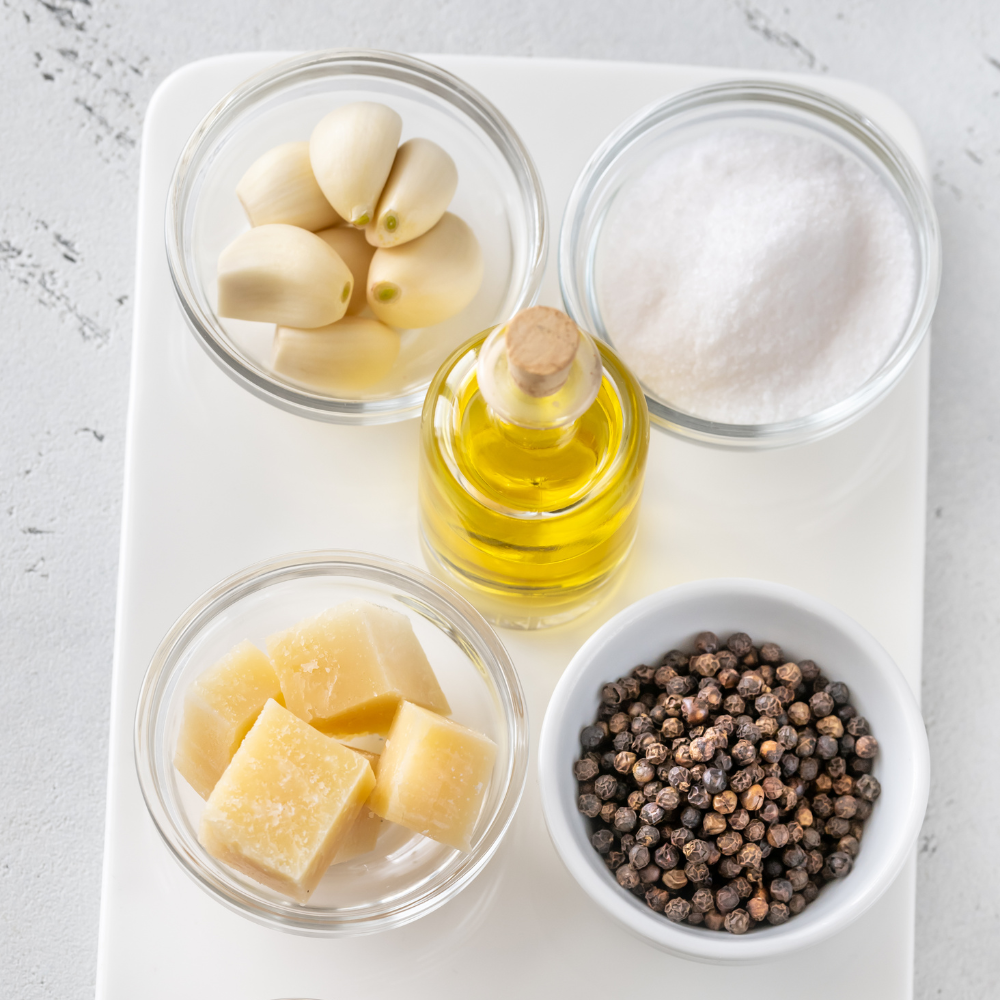 Fresh ingredients for kale pesto recipe including garlic, walnuts, Parmesan cheese, and olive oil.