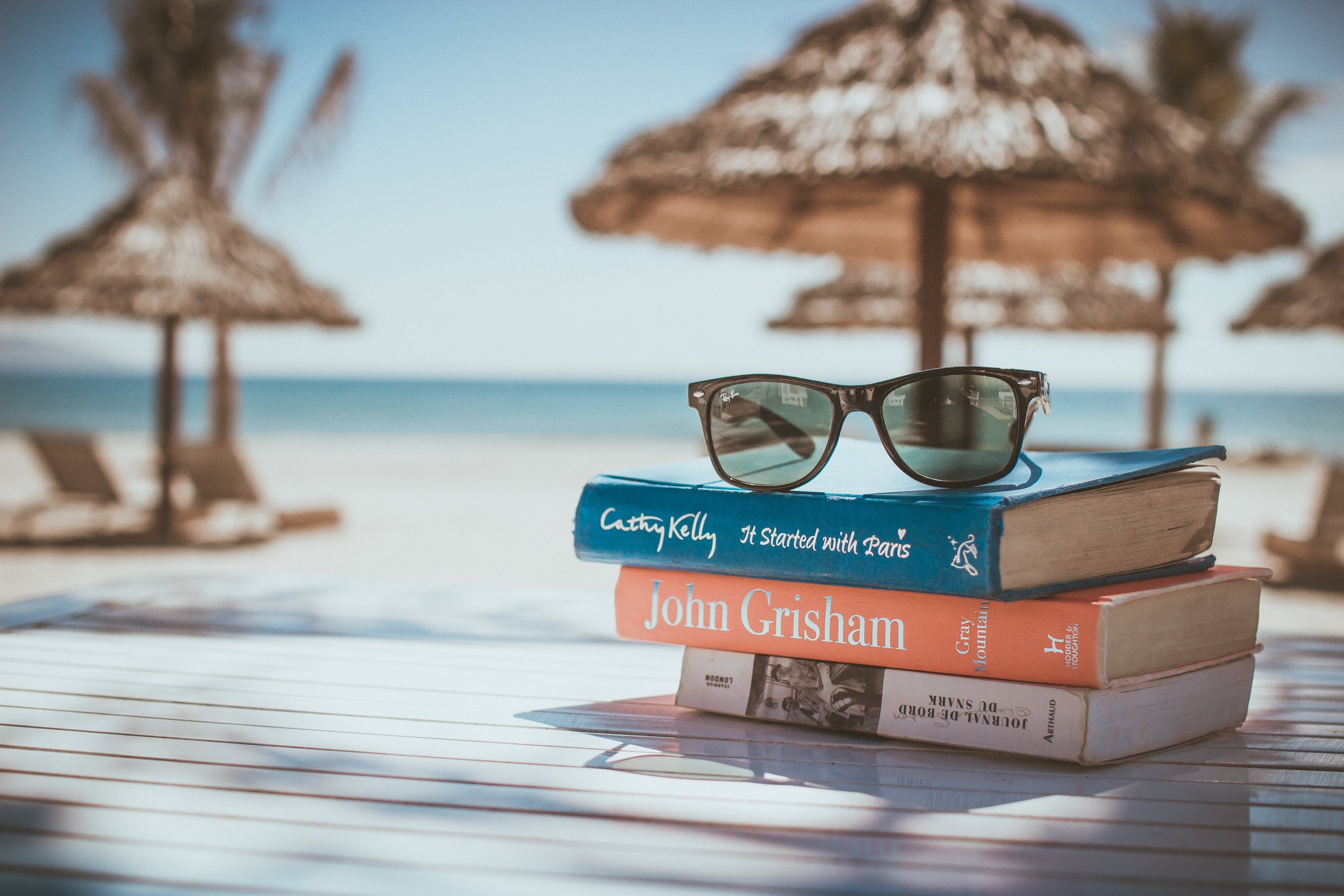 tree books on a table in a beach