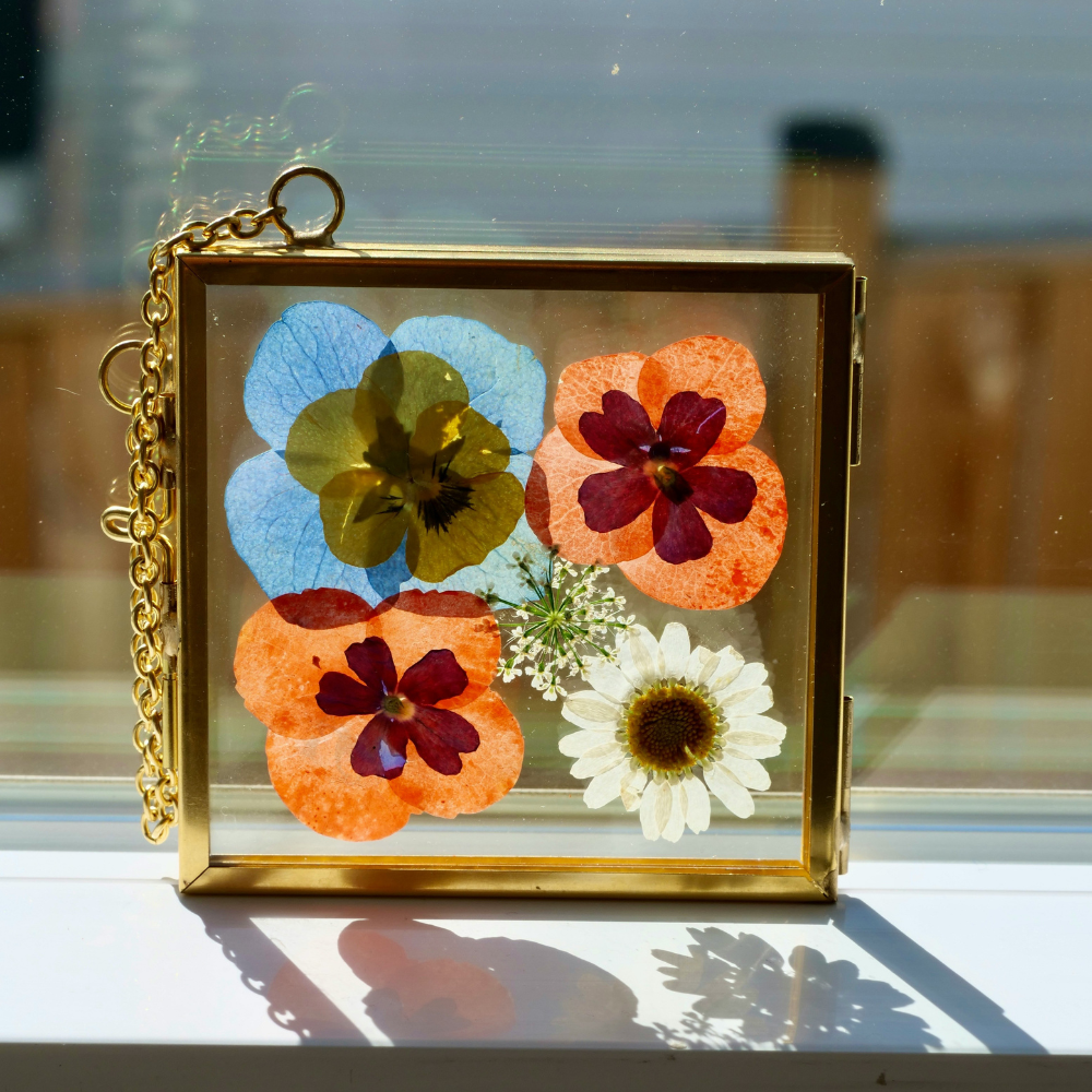 DIY pressed flower frame with dried flowers arranged in a floating glass frame for botanical wall art