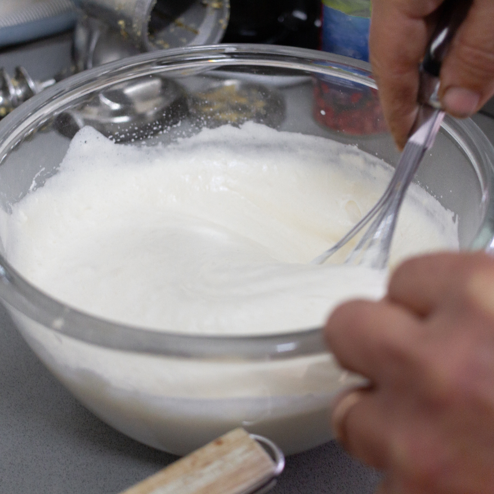 Freshly whipped cream in a mixing bowl for homemade strawberry shortcake.